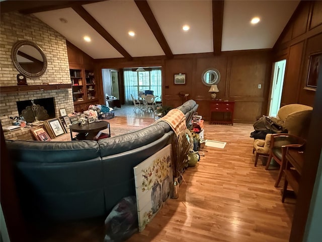 living area with lofted ceiling with beams, a fireplace, built in shelves, light wood-style flooring, and recessed lighting