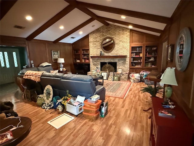living room featuring vaulted ceiling with beams, built in features, wood finished floors, and a fireplace