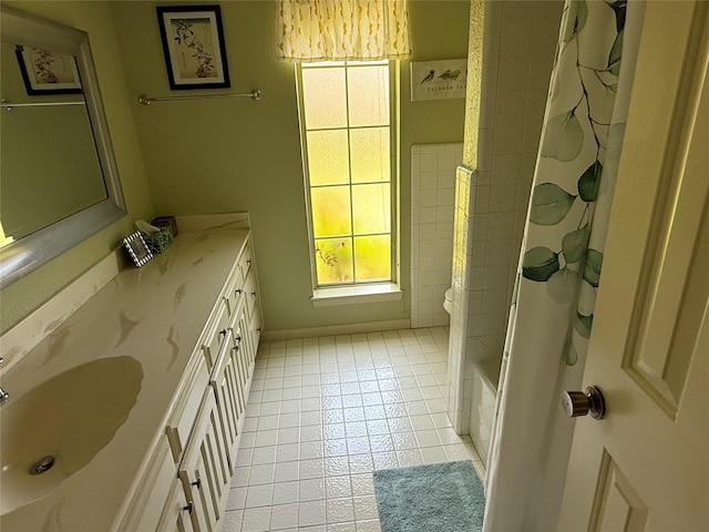 full bath featuring tile patterned flooring, double vanity, and a sink