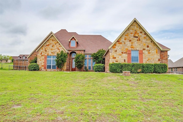 view of front of house featuring a front lawn, fence, and stone siding