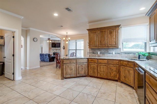 kitchen featuring visible vents, crown molding, stainless steel dishwasher, a fireplace, and a sink