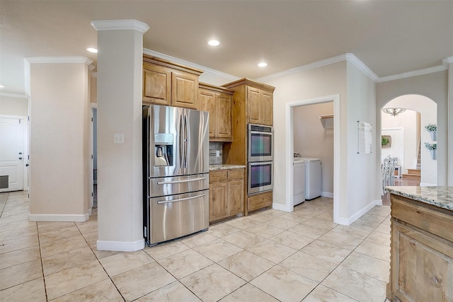 kitchen featuring crown molding, arched walkways, appliances with stainless steel finishes, and washing machine and dryer