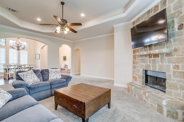 living room with visible vents, arched walkways, a raised ceiling, and light carpet