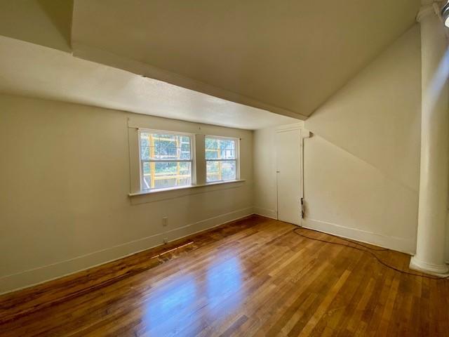 additional living space with baseboards and wood finished floors