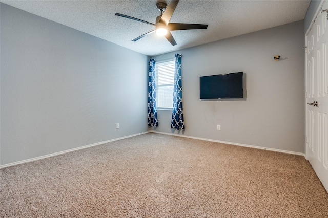 carpeted empty room with baseboards, ceiling fan, and a textured ceiling