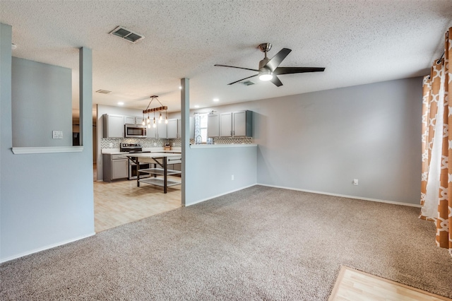 unfurnished living room featuring ceiling fan, visible vents, light carpet, and baseboards