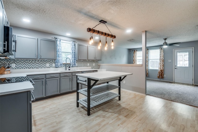 kitchen with backsplash, a textured ceiling, gray cabinetry, and a sink