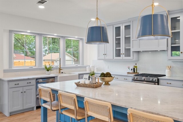 kitchen with a sink, plenty of natural light, light stone countertops, and stainless steel appliances