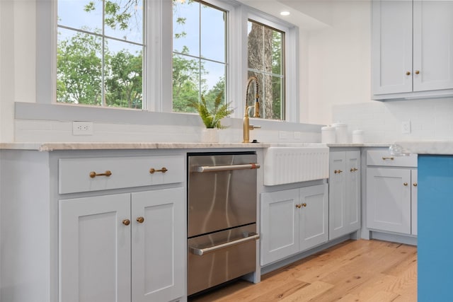 4401 El Campo Ave, Fort Worth, TX 76107 - kitchen with a sink, light wood-type flooring, decorative backsplash, stainless steel dishwasher, and light stone countertops