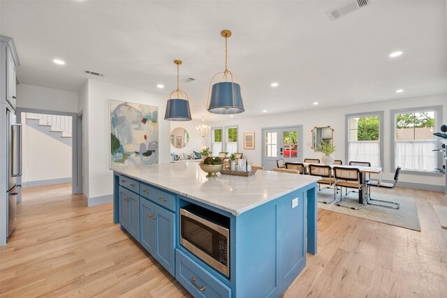 kitchen with stainless steel appliances, visible vents, light wood finished floors, and blue cabinets