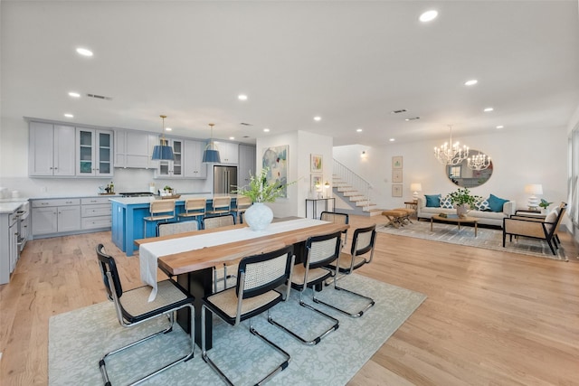 dining space featuring visible vents, an inviting chandelier, stairs, recessed lighting, and light wood-style flooring