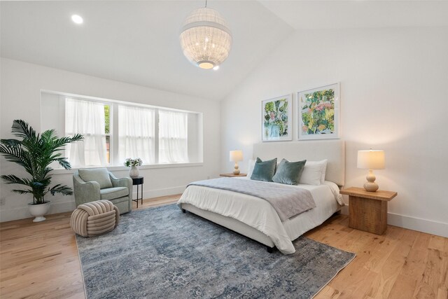bedroom featuring an inviting chandelier, baseboards, light wood finished floors, and high vaulted ceiling
