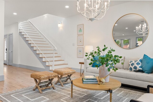 living area featuring a chandelier, recessed lighting, baseboards, wood finished floors, and stairway