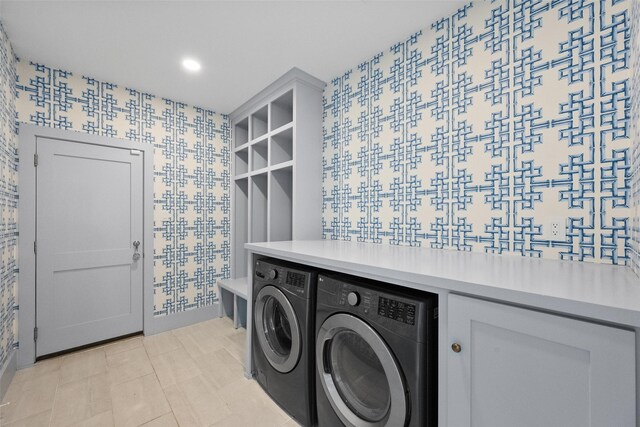 washroom with laundry area, an accent wall, washer and dryer, and wallpapered walls