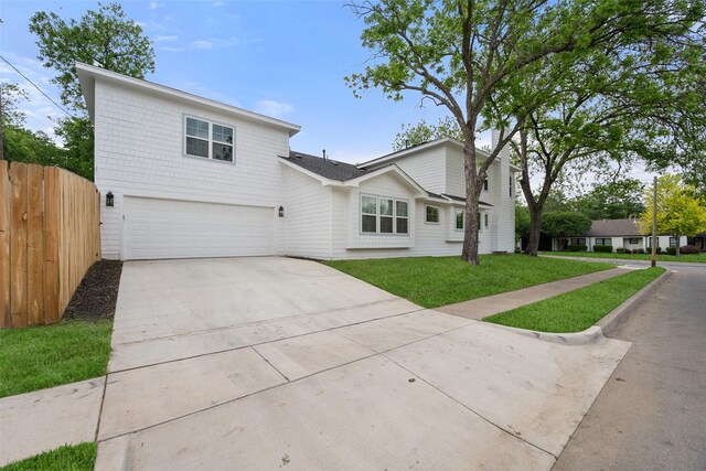 view of front facade with a garage, fence, driveway, and a front yard