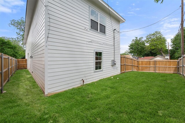 rear view of property featuring a lawn and a fenced backyard
