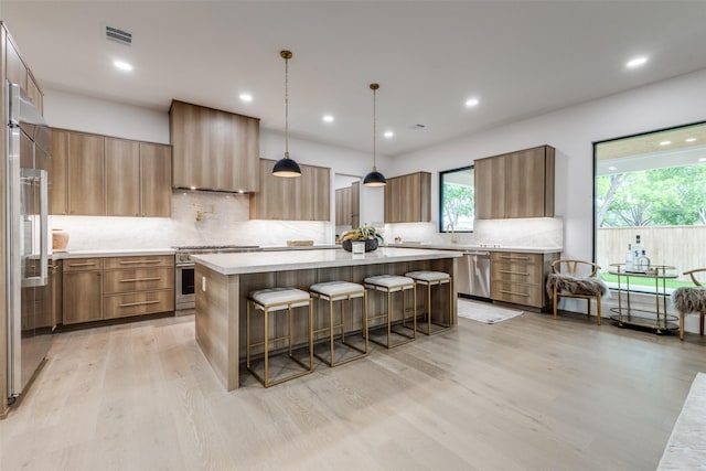 kitchen with high quality appliances, a kitchen breakfast bar, decorative backsplash, a kitchen island, and visible vents