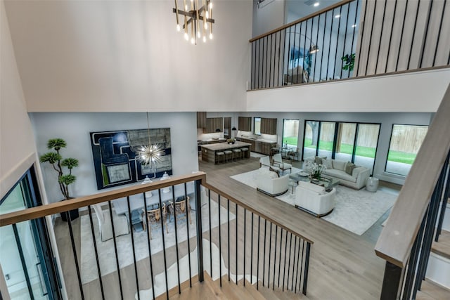living area featuring wood finished floors, a high ceiling, and an inviting chandelier