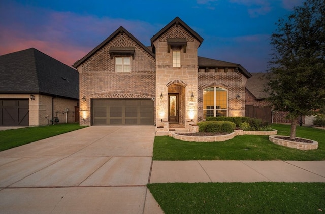 view of front of home featuring driveway, brick siding, a yard, an attached garage, and stone siding