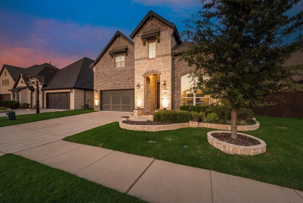 french country style house featuring driveway, brick siding, fence, a yard, and stone siding