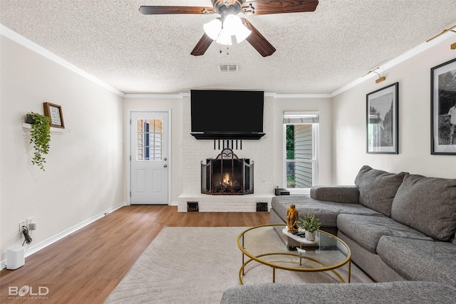 living room featuring ornamental molding, a brick fireplace, wood finished floors, and visible vents