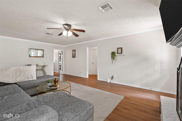 living area featuring a ceiling fan, visible vents, ornamental molding, and wood finished floors