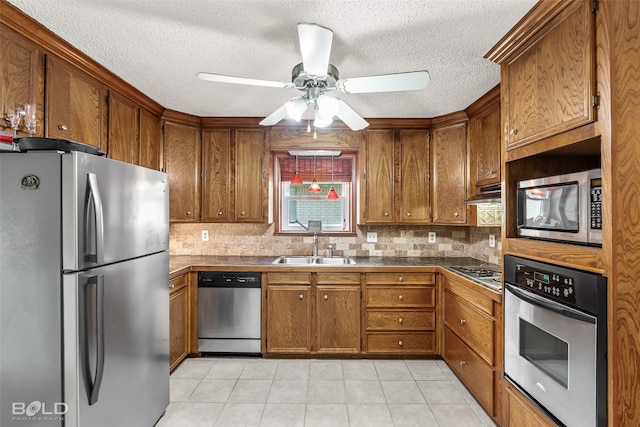 kitchen with brown cabinetry, a sink, decorative backsplash, and appliances with stainless steel finishes
