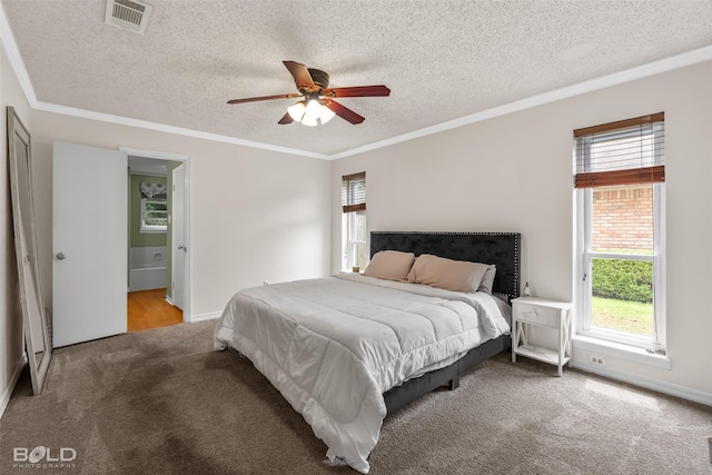 bedroom featuring a textured ceiling, visible vents, connected bathroom, ornamental molding, and carpet