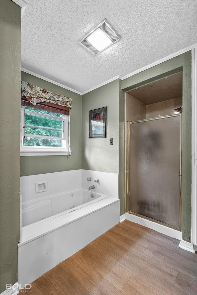 bathroom with a garden tub, a textured ceiling, visible vents, a shower stall, and wood finished floors