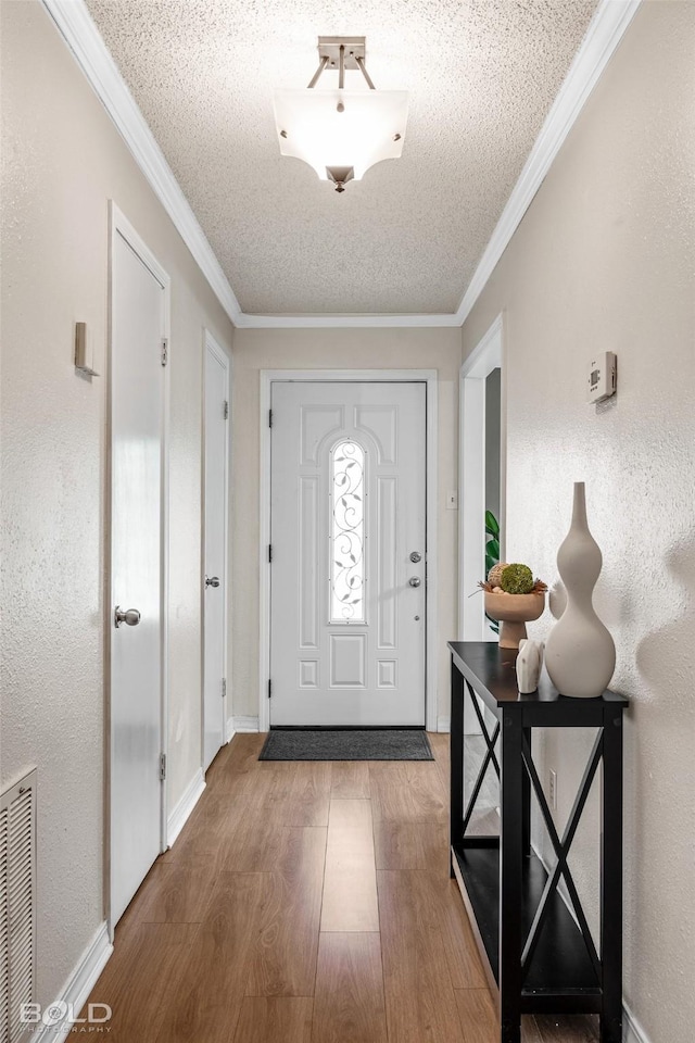 entryway featuring crown molding, a textured ceiling, visible vents, and wood finished floors
