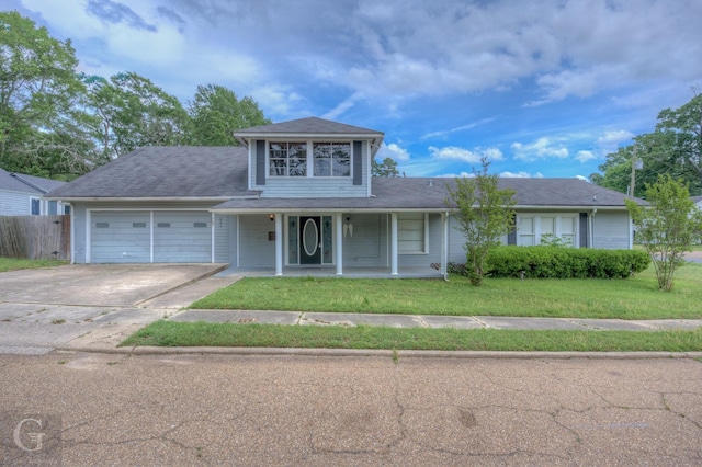 traditional-style home featuring fence, covered porch, a front yard, an attached garage, and driveway