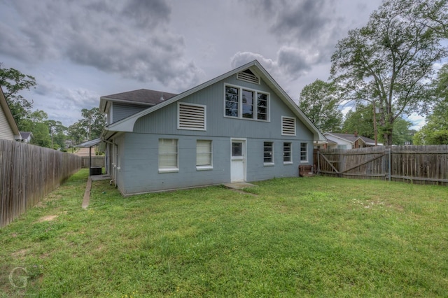 rear view of house with a fenced backyard, concrete block siding, and a yard