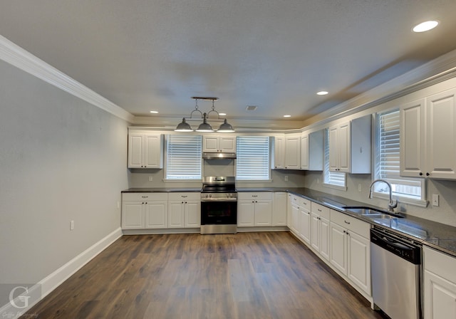kitchen with white cabinets, stainless steel appliances, dark countertops, and a sink