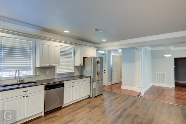 kitchen featuring visible vents, dark countertops, appliances with stainless steel finishes, a sink, and ornamental molding