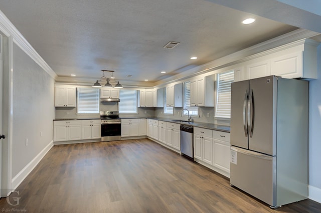 kitchen featuring crown molding, dark countertops, white cabinetry, a sink, and appliances with stainless steel finishes