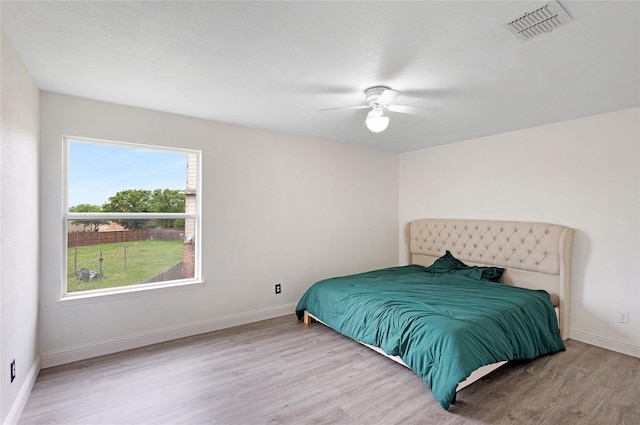 bedroom with visible vents, a ceiling fan, baseboards, and wood finished floors