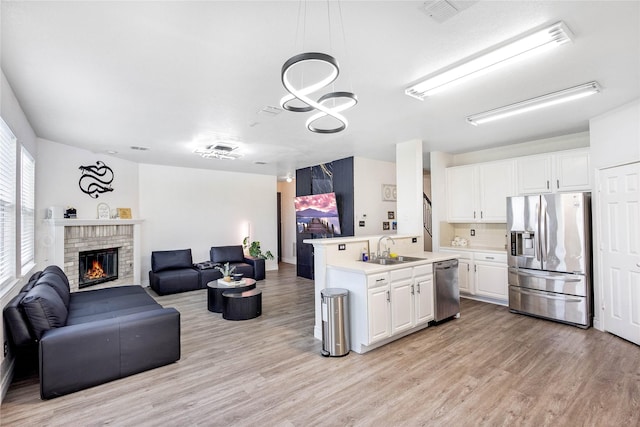 kitchen featuring a sink, light countertops, stainless steel appliances, open floor plan, and light wood-type flooring