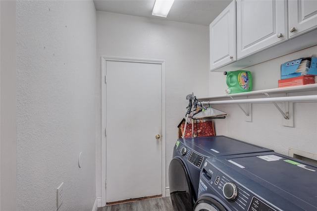 laundry area with cabinet space, independent washer and dryer, a textured wall, and wood finished floors