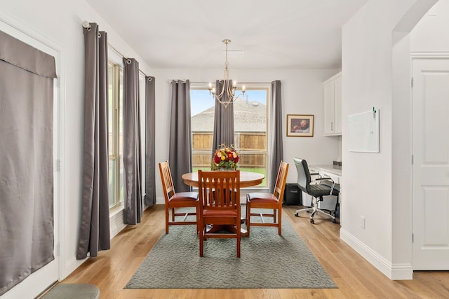 dining area with baseboards, an inviting chandelier, and light wood-type flooring