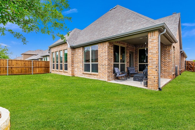 back of property with roof with shingles, a fenced backyard, a patio area, and brick siding
