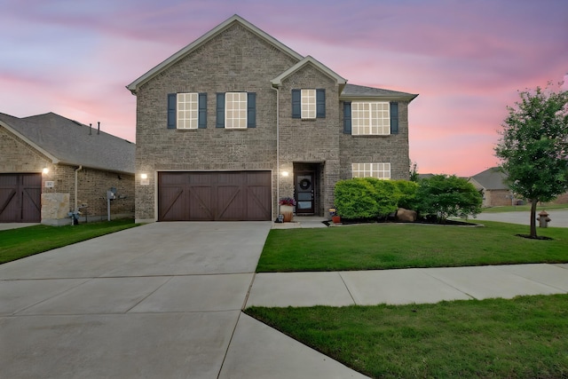 traditional-style house featuring a yard, an attached garage, and driveway