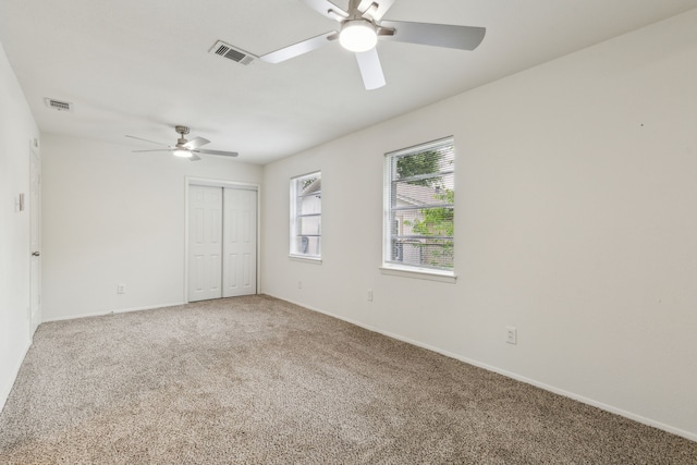 unfurnished bedroom with carpet flooring, visible vents, and a closet