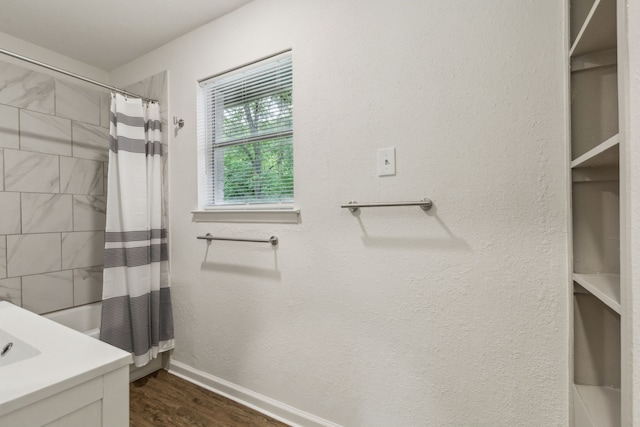 full bath featuring baseboards, vanity, wood finished floors, and shower / bath combo with shower curtain