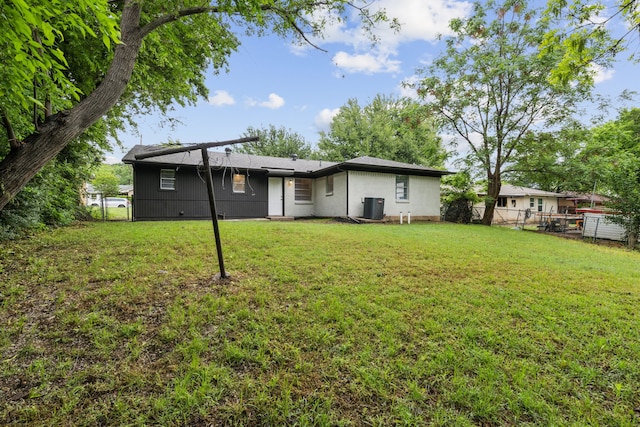 rear view of house with fence, a yard, and cooling unit