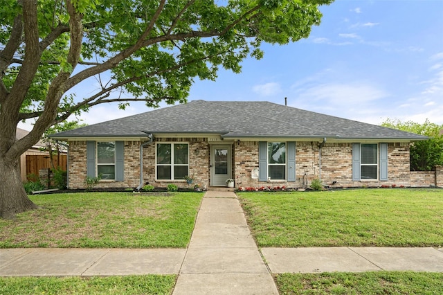 ranch-style house featuring brick siding, a shingled roof, a front lawn, and fence