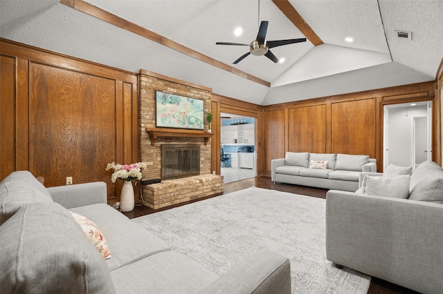living room featuring a ceiling fan, visible vents, a fireplace, wood finished floors, and lofted ceiling