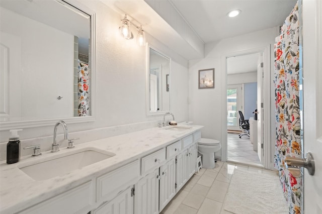 full bath featuring double vanity, toilet, a sink, and tile patterned flooring