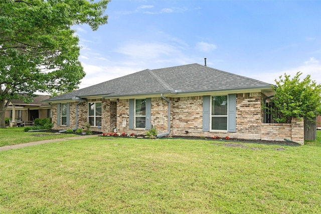 ranch-style house featuring roof with shingles, a front lawn, and brick siding