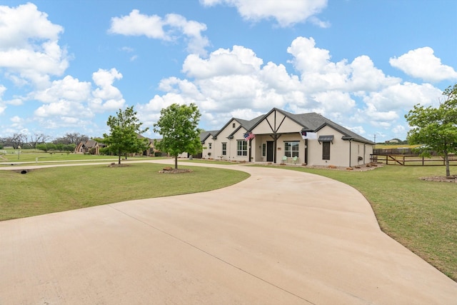 view of front facade featuring stucco siding, curved driveway, fence, and a front lawn