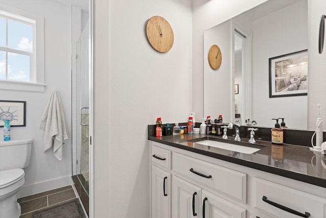 bathroom featuring tile patterned flooring, a shower stall, vanity, baseboards, and toilet